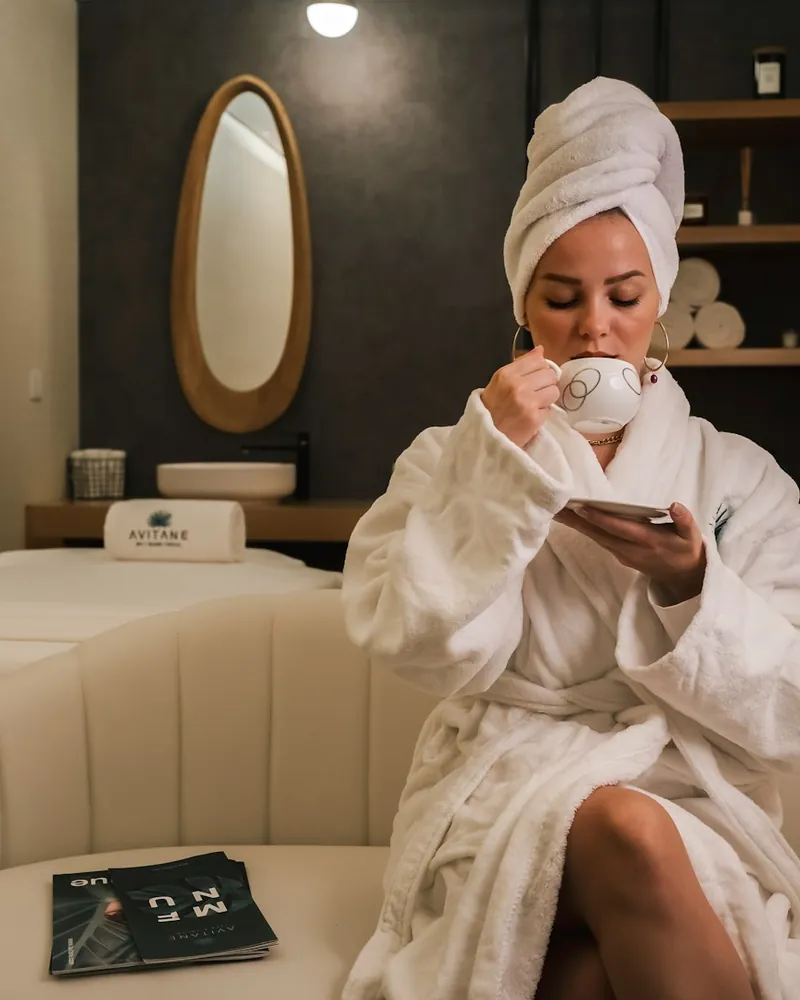 A woman in a bathrobe with a cup of tea at a spa, sample photo