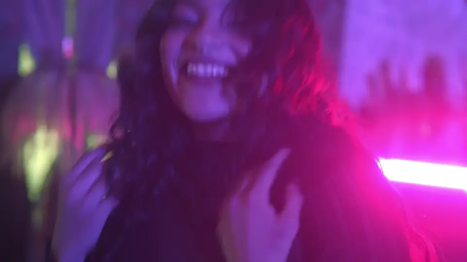 A woman dancing under neon lights, still from a sample video