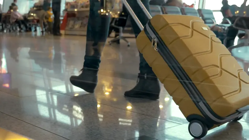 A traveller pulling a suitcase through an airport, still from a sample video